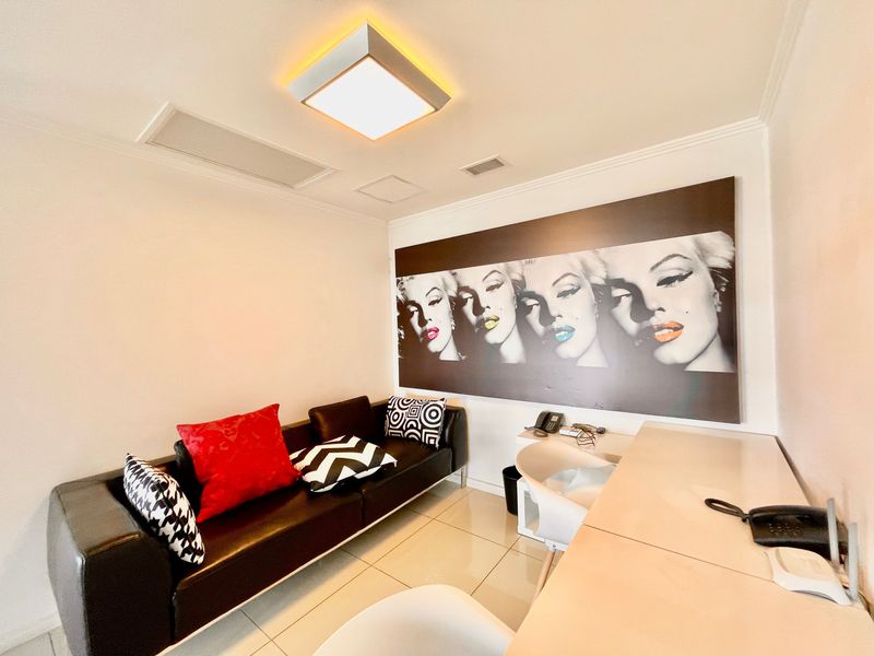A compact living area featuring tiled flooring, recessed ceiling lighting, and integrated ducted air conditioning.