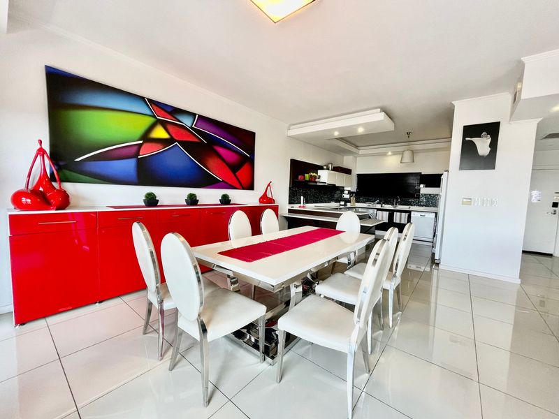 Open-plan dining and kitchen area featuring polished floor tiles, modern cabinetry, and recessed ceiling lighting in a well-maintained apartment setting.