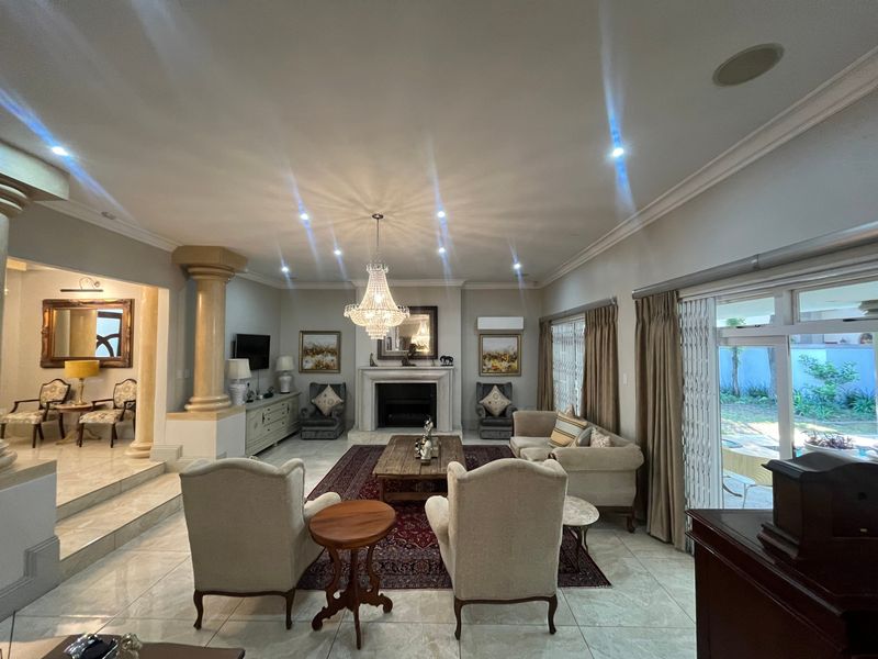 Spacious living room featuring a central fireplace, decorative columns, tiled flooring, and large sliding glass doors providing access to the outdoor area.