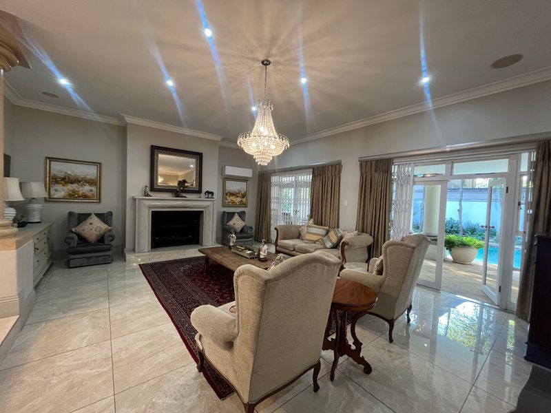 Spacious living room featuring a fireplace with a marble mantelpiece, tiled flooring, recessed lighting, and direct access to the outdoor pool area.