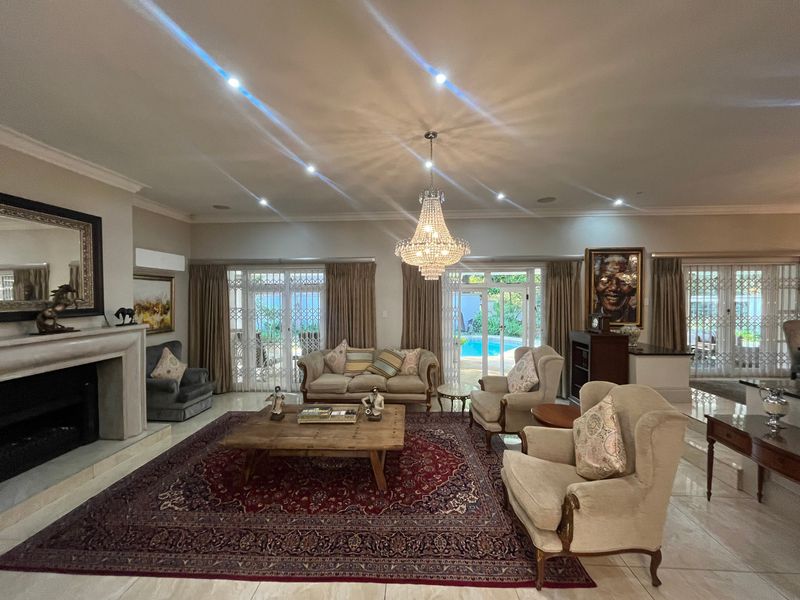 Spacious living room featuring a fireplace, crystal chandelier, recessed lighting, and large sliding glass doors providing direct access to the pool area.