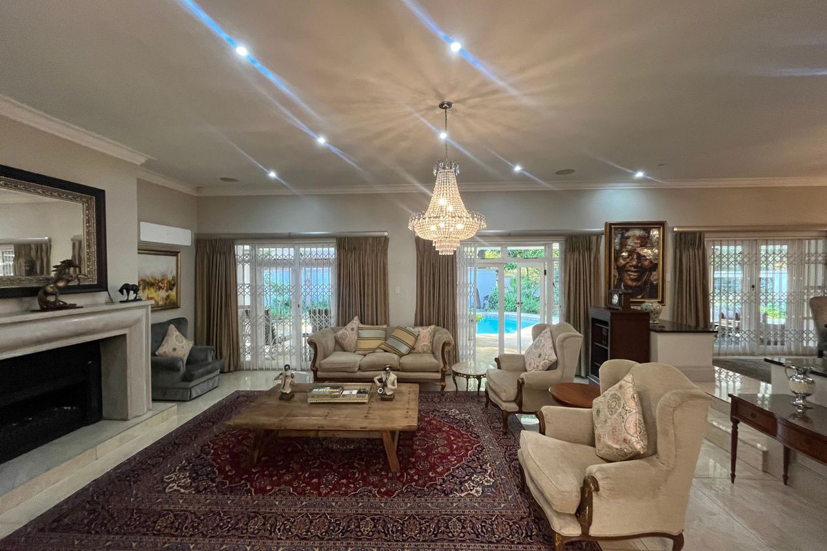 Spacious living room featuring a fireplace, crystal chandelier, recessed lighting, and large sliding glass doors providing direct access to the pool area.