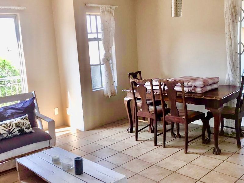 Open-plan living and dining area featuring tiled flooring, large windows for natural light, and direct access to a balcony through a sliding glass door.