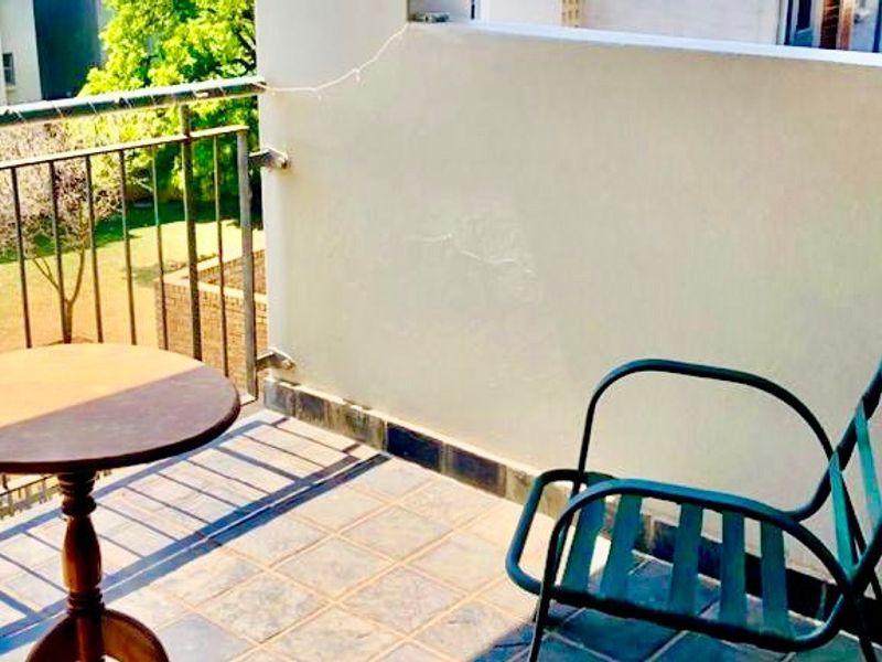 A compact balcony featuring tiled flooring and a metal balustrade, offering an outdoor space with views of the surrounding complex grounds.