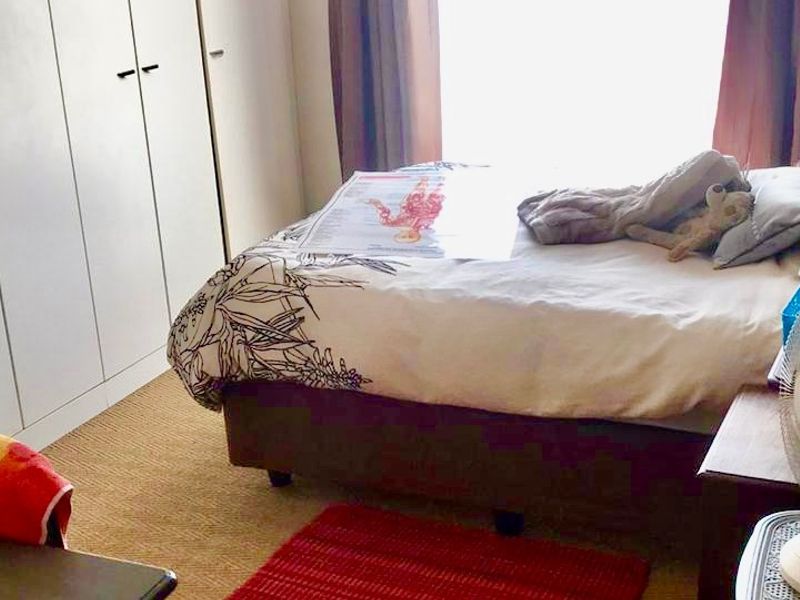 A bedroom featuring built-in cupboards and carpeted flooring, providing functional storage space.