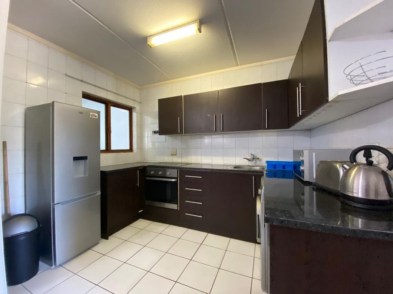 A functional kitchen featuring dark wood cabinetry, granite countertops, tiled backsplash, and built-in oven with hob.