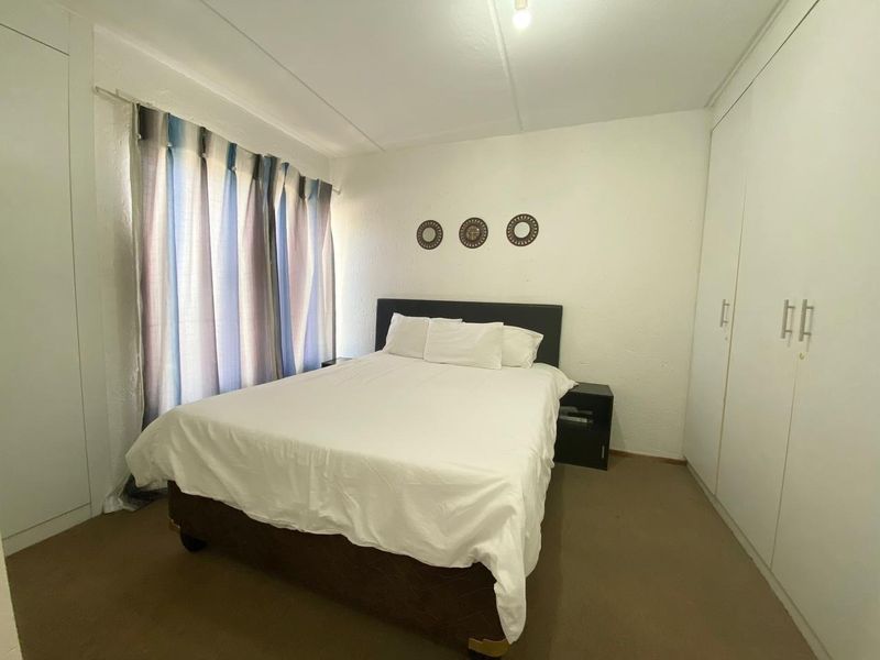 A functional bedroom featuring built-in cupboards and neutral carpeting, offering a clean and simple space.