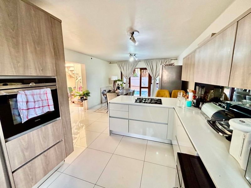 Modern open-plan kitchen featuring sleek cabinetry, stone countertops, integrated oven, and gas hob, flowing seamlessly into the dining and living area.