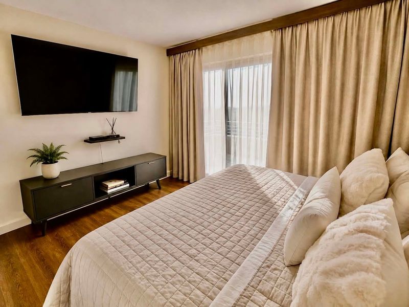 A well-maintained bedroom featuring laminate flooring and a sliding glass door with floor-to-ceiling curtains providing access to an outdoor area.