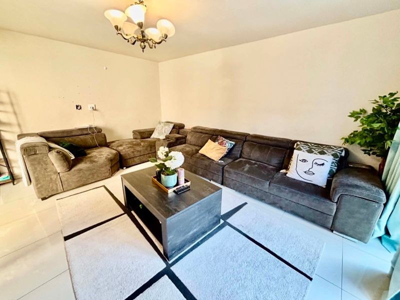 A living room featuring tiled flooring and a central ceiling light fixture, with visible wall surface imperfections.
