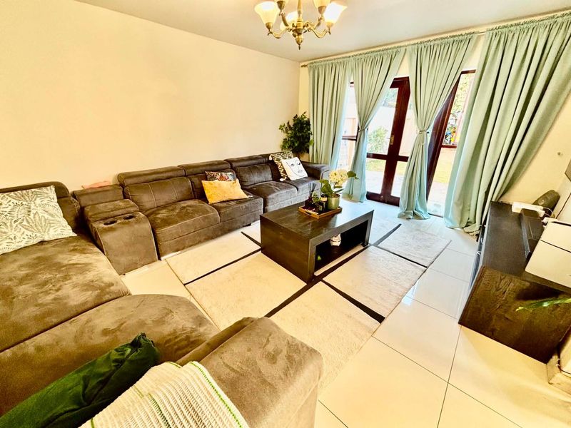 A comfortable living room featuring tiled flooring and double glass doors providing access to the outdoor area.