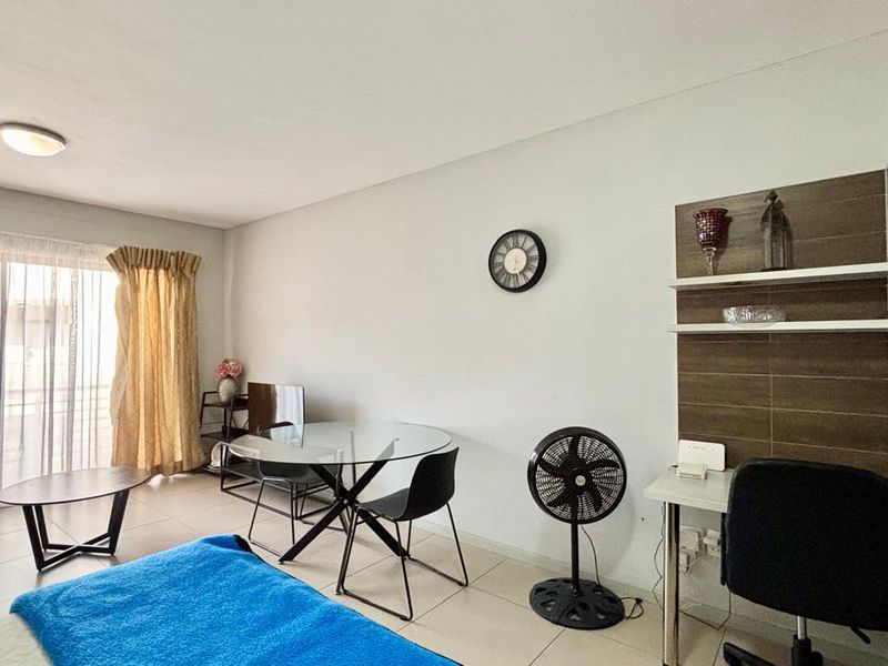 A living area featuring tiled flooring, a sliding glass door providing natural light, and a built-in wall shelving unit.