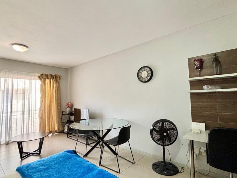 A living area featuring tiled flooring, a built-in wall shelving unit, and a sliding glass door providing access to the exterior.
