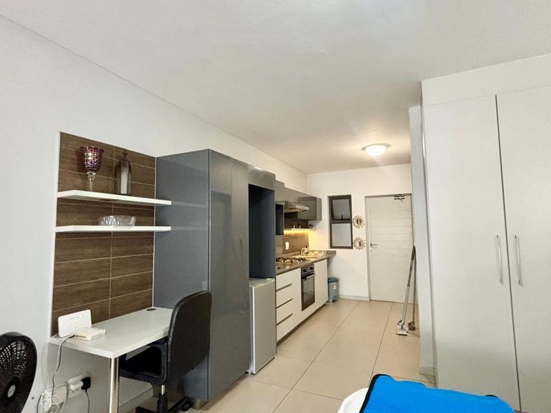 Modern open-plan kitchen featuring sleek cabinetry, built-in oven, gas hob, and extractor fan, seamlessly integrated with a functional workspace and ample storage cupboards.