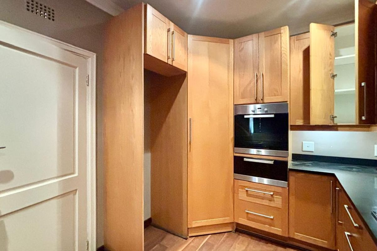 A functional kitchen featuring light wood cabinetry, built-in oven and microwave, and dark stone countertops with ample storage space.