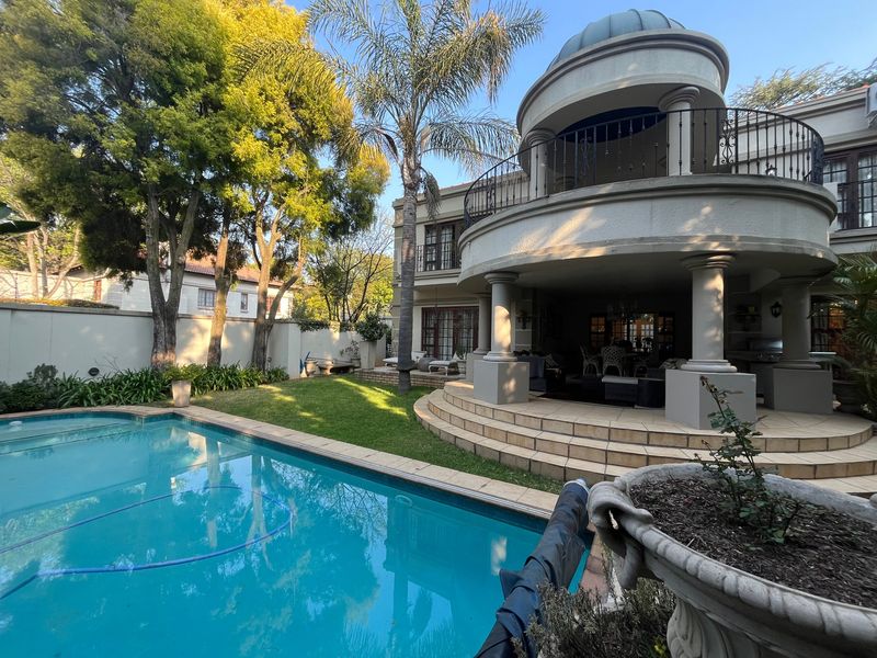 Rear exterior view featuring a swimming pool, a covered patio area, and a distinctive upper-level balcony with a dome architectural detail.