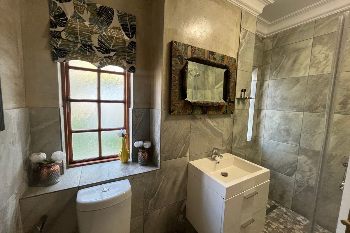 A modern bathroom featuring a vanity cabinet with basin, a toilet, and a tiled shower enclosure with contemporary wall and floor finishes.