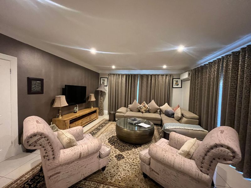 A comfortable living room featuring tiled flooring, recessed downlighting, and an integrated air conditioning unit, providing a functional and well-maintained space.