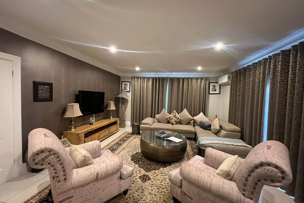 A comfortable living room featuring tiled flooring, recessed downlighting, and an integrated air conditioning unit, providing a functional and well-maintained space.