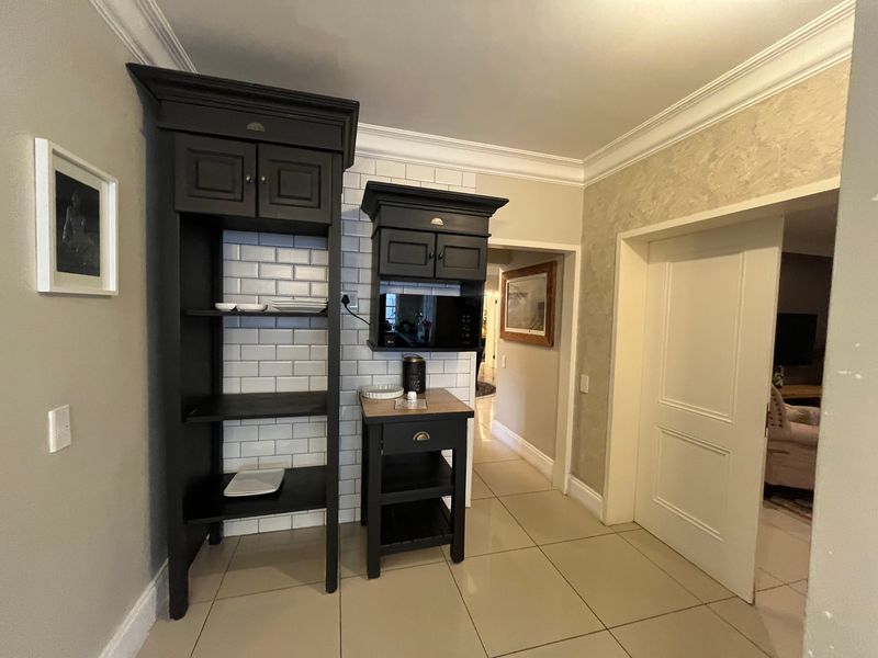 A functional scullery or prep area featuring dark built-in cabinetry, a classic subway tile backsplash, and neutral floor tiles.