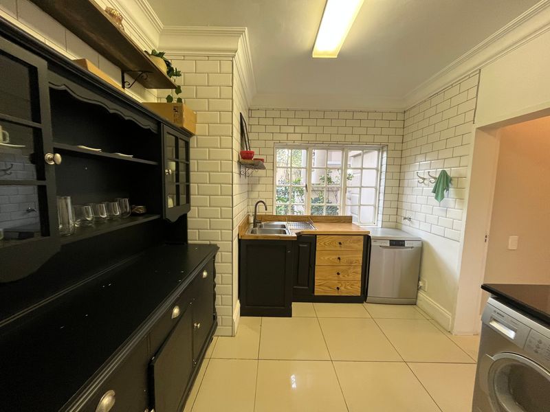 A functional scullery featuring subway tile backsplash, wooden countertops, stainless steel sink, and ample built-in cabinetry for storage and utility tasks.