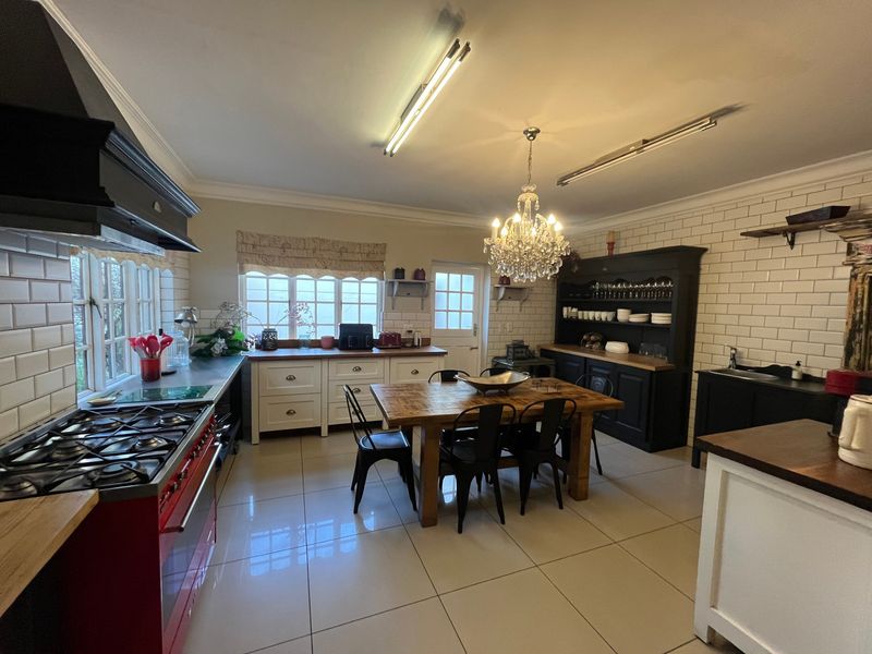 Spacious open-plan kitchen and dining area featuring a large gas range, subway tile backsplash, timber countertops, and modern porcelain floor tiles.
