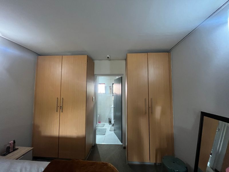 Bedroom featuring dual built-in wooden cupboards and direct access to an en-suite bathroom.