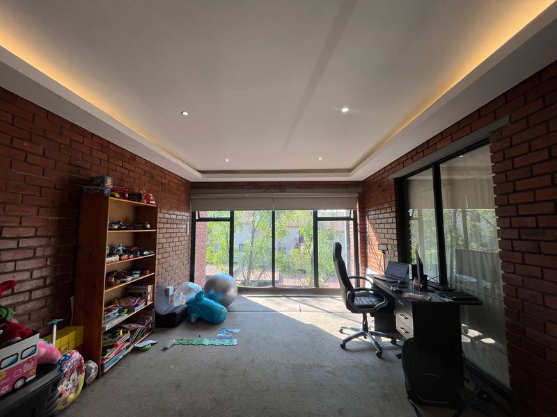 Spacious bedroom featuring exposed brick walls, recessed ceiling lighting, and large windows providing ample natural light.