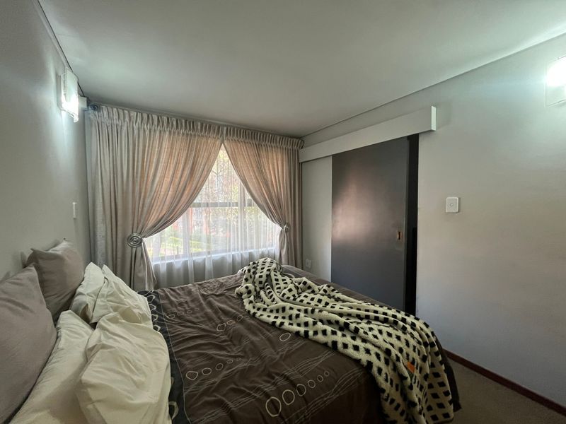 A cozy bedroom featuring a sliding door, neutral wall finishes, and window treatments, providing a functional and comfortable sleeping space.