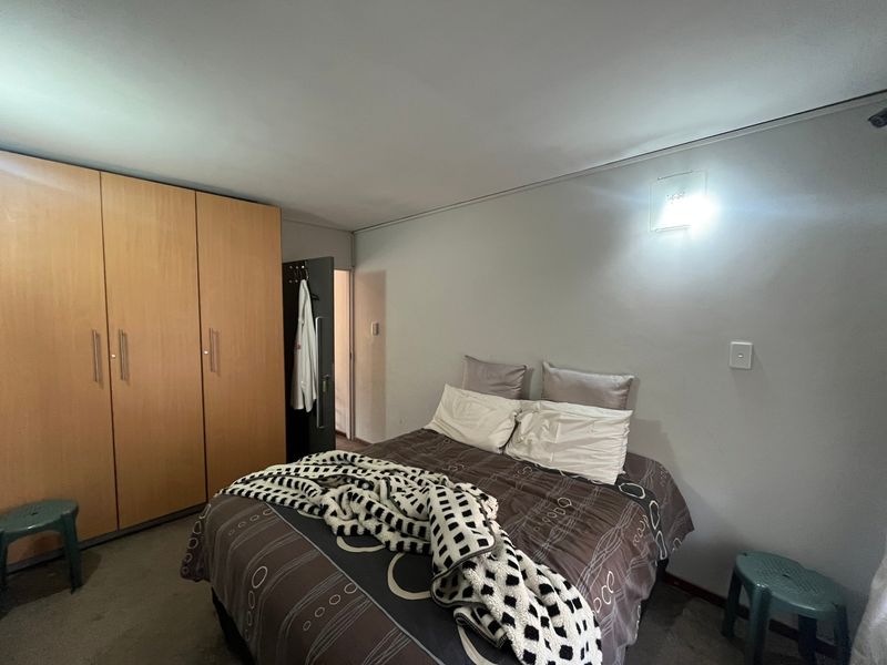 A bedroom featuring built-in wooden cupboards and a wall-mounted light fixture.