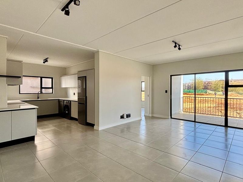 Modern open-plan living area featuring a sleek kitchen with built-in cabinetry, tiled floors, and large sliding doors leading to a private balcony.