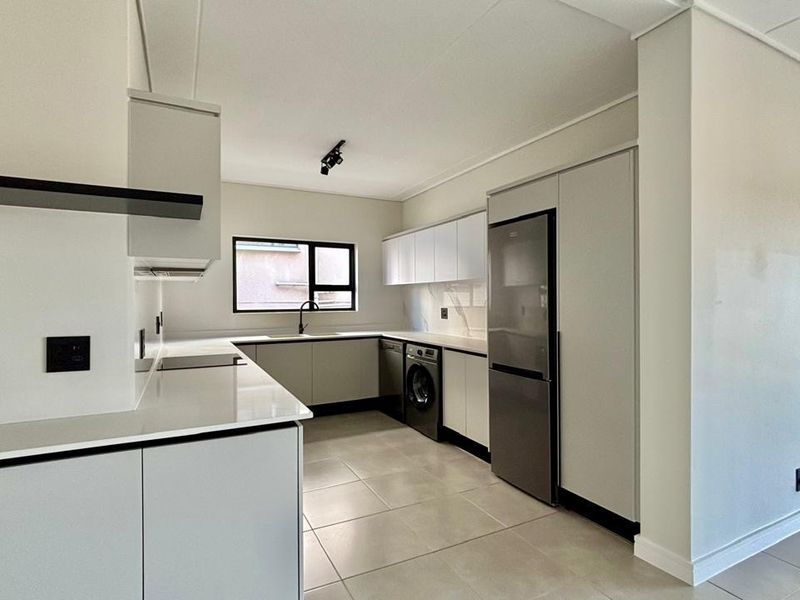 Modern, minimalist kitchen featuring sleek cabinetry, quartz countertops, integrated appliances, and neutral tiled flooring in a clean, open-plan layout.