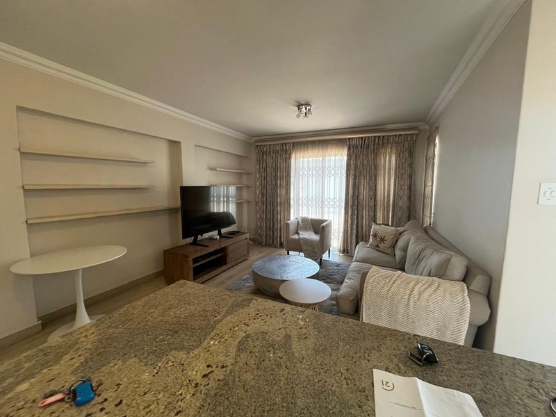 Open plan living area featuring built-in wall shelving, granite kitchen counter, and sliding door access to the exterior.