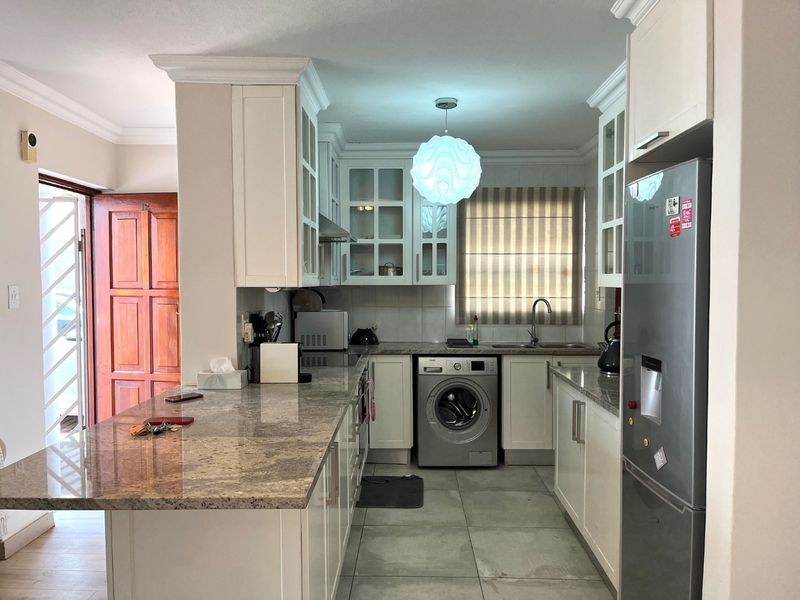 A well-maintained kitchen featuring granite countertops, shaker-style cabinetry, integrated appliances, and tiled flooring, offering a functional and clean culinary space.