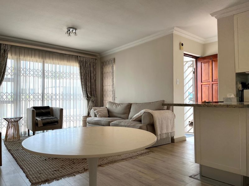 Open plan living area featuring laminate flooring, granite kitchen counter, and large sliding glass doors with security gate leading to the exterior.