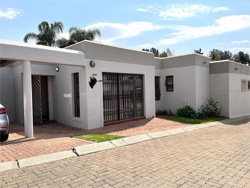 Front elevation of a townhouse featuring a paved driveway, security gates, and sliding door access.