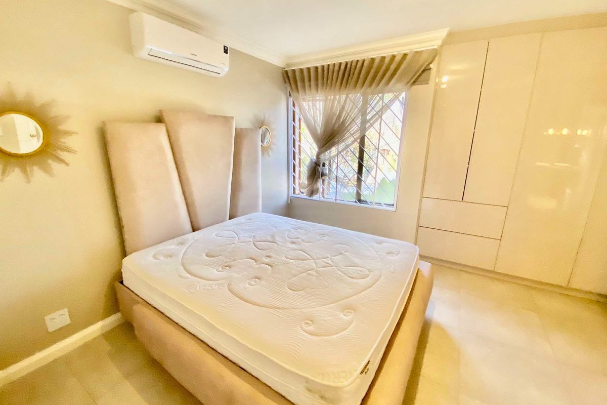 A well-maintained bedroom featuring built-in cupboards, tiled flooring, and a wall-mounted air conditioning unit, offering a clean and functional living space.