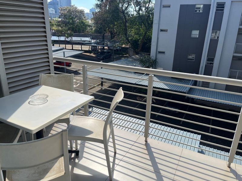 A private balcony featuring tiled flooring and a metal balustrade, offering an elevated view of the complex parking area.