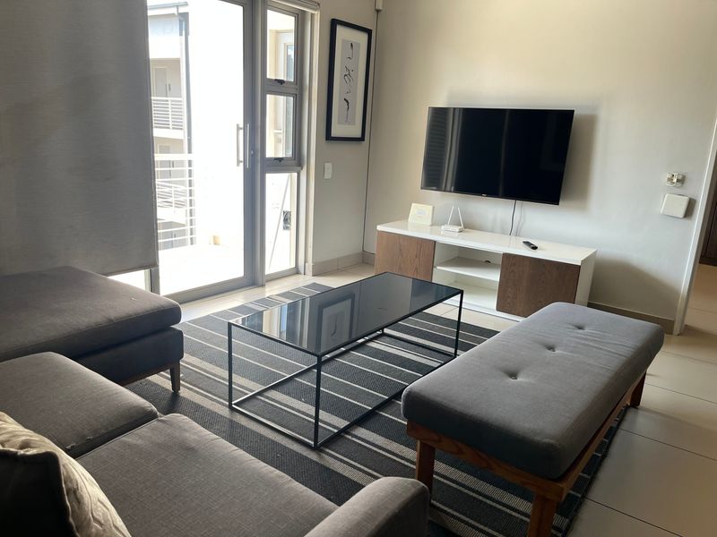 A well-maintained living room featuring tiled flooring and a large sliding glass door providing access to an outdoor area.