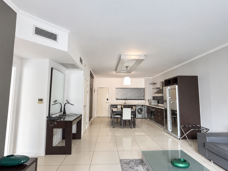 Spacious open-plan living and kitchen area featuring modern tiled flooring, ducted air conditioning, and sleek built-in cabinetry with integrated appliances.