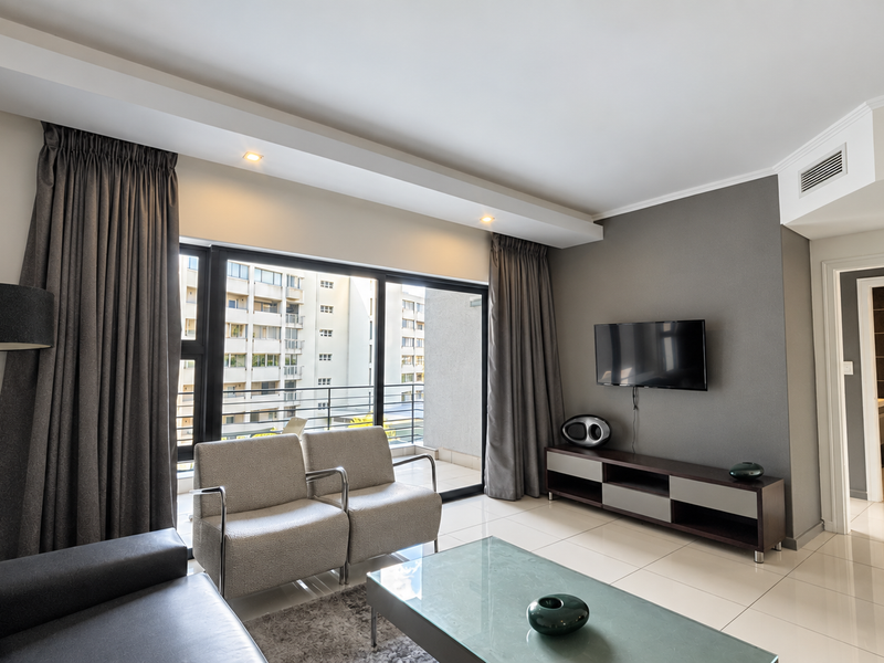 Modern living room featuring tiled flooring, recessed ceiling lighting, and large sliding glass doors providing access to the balcony.