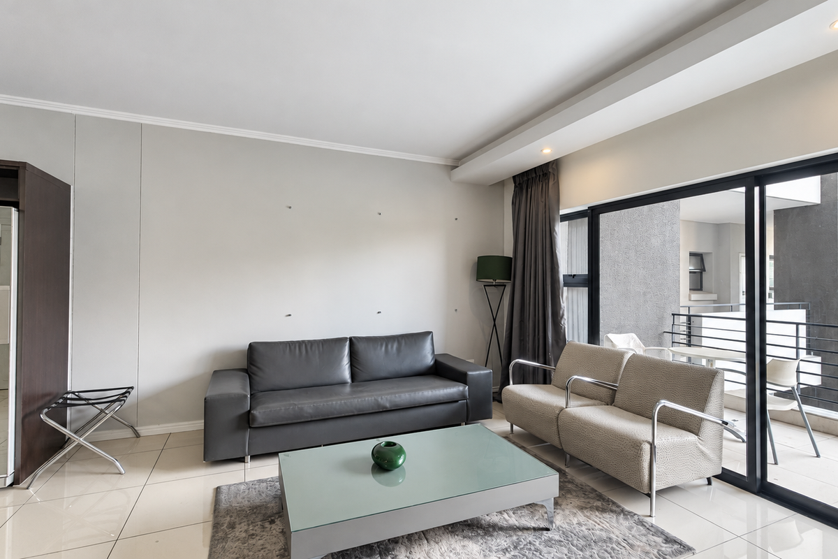 A bright living room featuring tiled flooring, recessed ceiling lighting, and large sliding glass doors that provide access to an attached balcony.