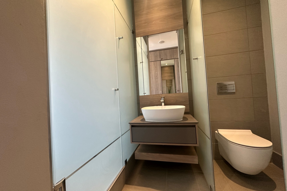 Modern bathroom featuring a floating vanity with a vessel sink, wall-mounted toilet with concealed cistern, and frosted glass partitions.