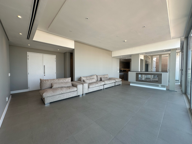 Spacious open-plan living area featuring large format floor tiles, recessed ceiling lighting, ducted air conditioning, and a modern built-in fireplace.
