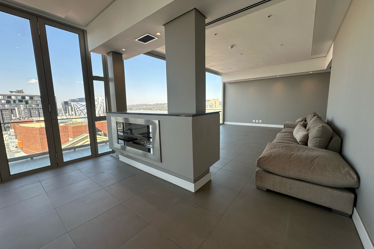 Spacious open-plan living area featuring a modern built-in fireplace, large format floor tiles, and expansive floor-to-ceiling windows with panoramic city views.