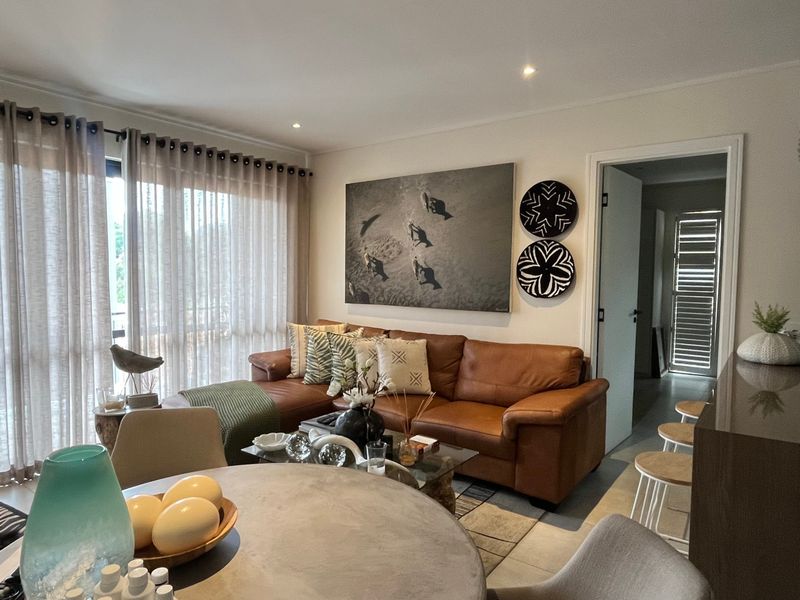 A well-lit open-plan living and dining area featuring modern recessed lighting and large sliding glass doors leading to an outdoor space.