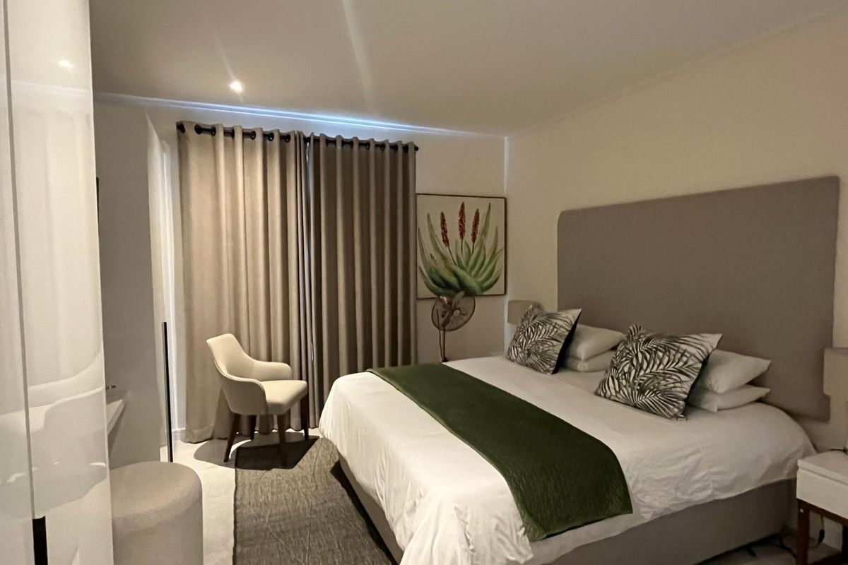 A well-maintained bedroom featuring a built-in wardrobe, recessed lighting, and large sliding doors leading to an outdoor area.