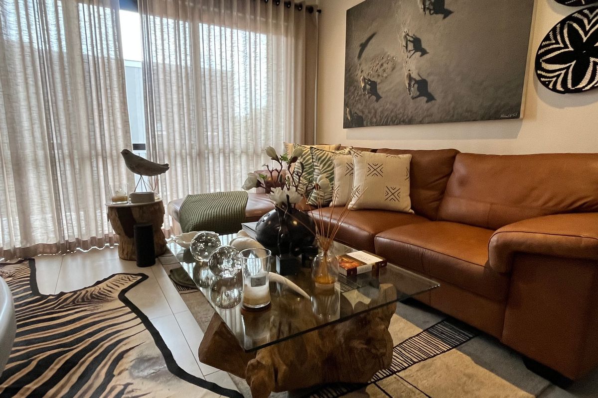 A well-maintained living room featuring tiled flooring and large sliding glass doors that provide ample natural light.