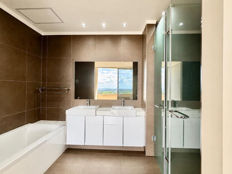 Modern bathroom featuring a double vanity, built-in bathtub, and a separate glass-enclosed shower with contemporary tiled finishes.