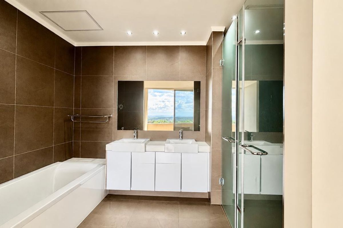 Modern bathroom featuring a double vanity, built-in bathtub, and a separate glass-enclosed shower with contemporary tiled finishes.